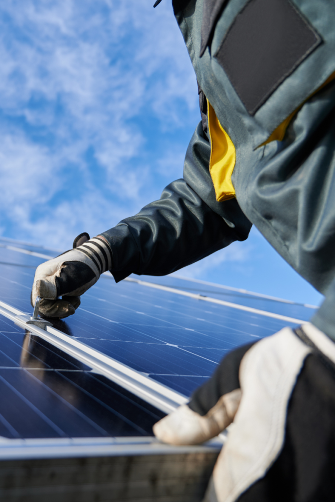 Closeup of a person with gloves installing a solar panel on a roof
